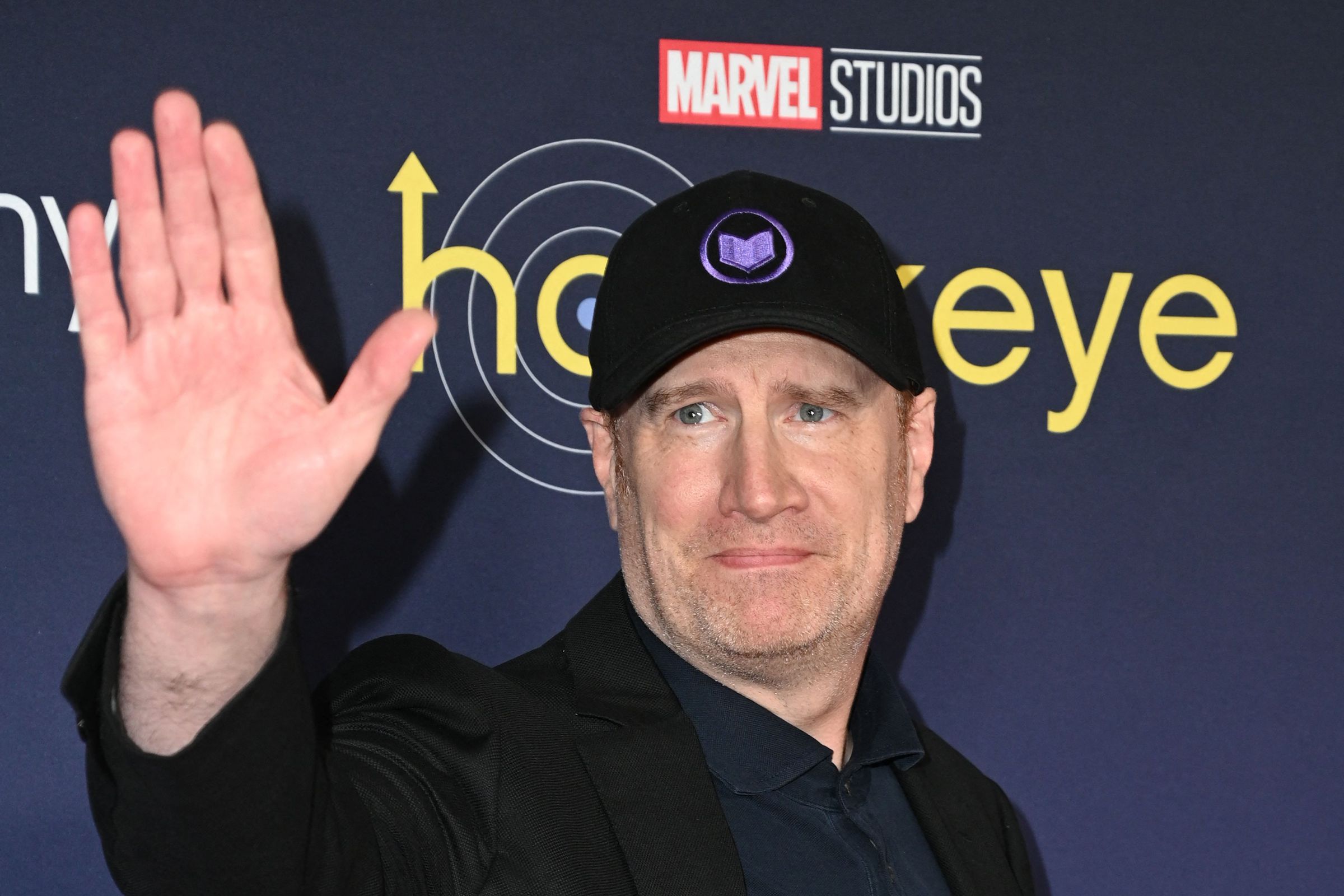 A picture of Kevin Feige waving to someone out of frame.