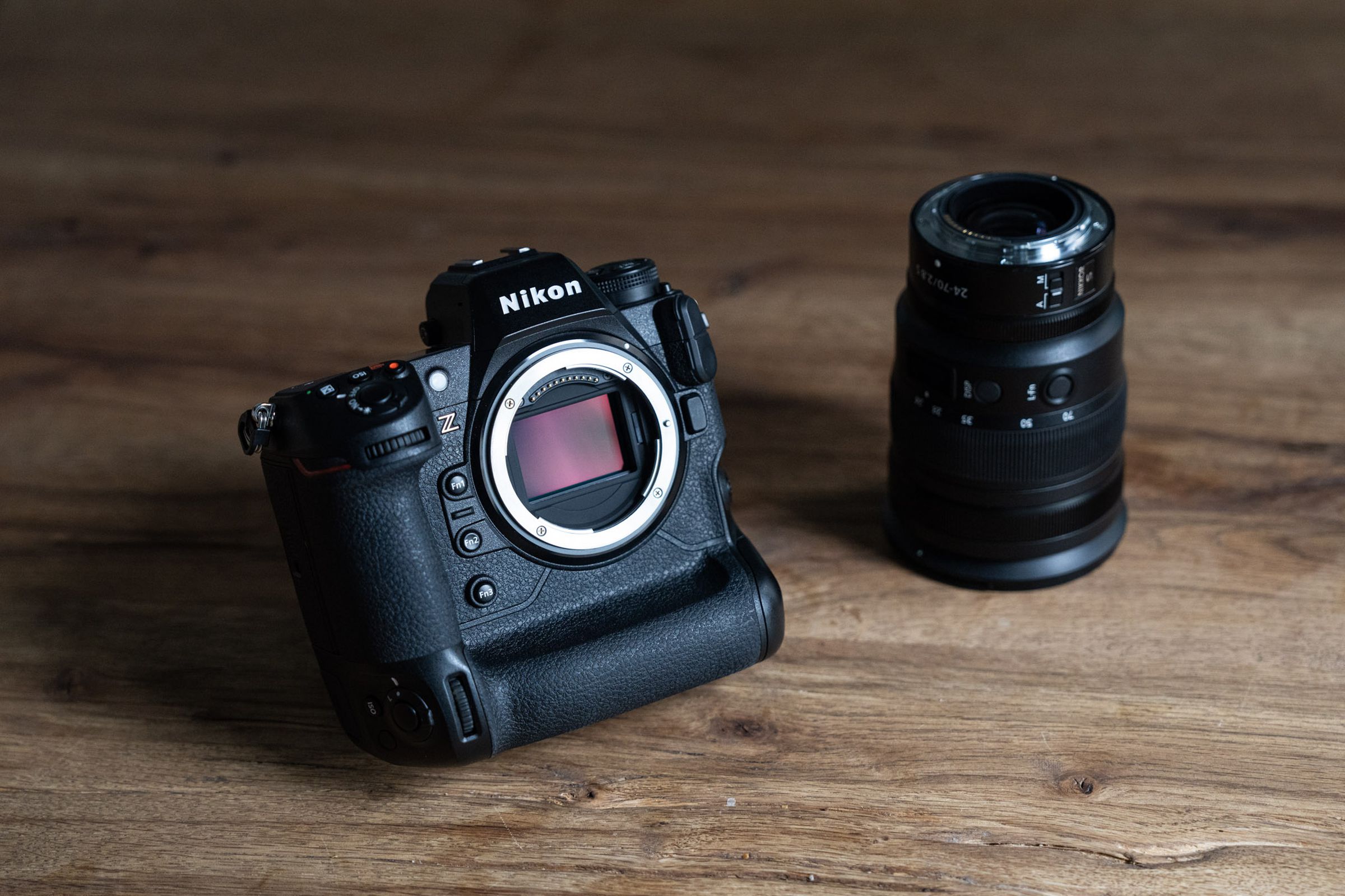 A Nikon Z9 camera sitting on a wood table with its lens next to it.