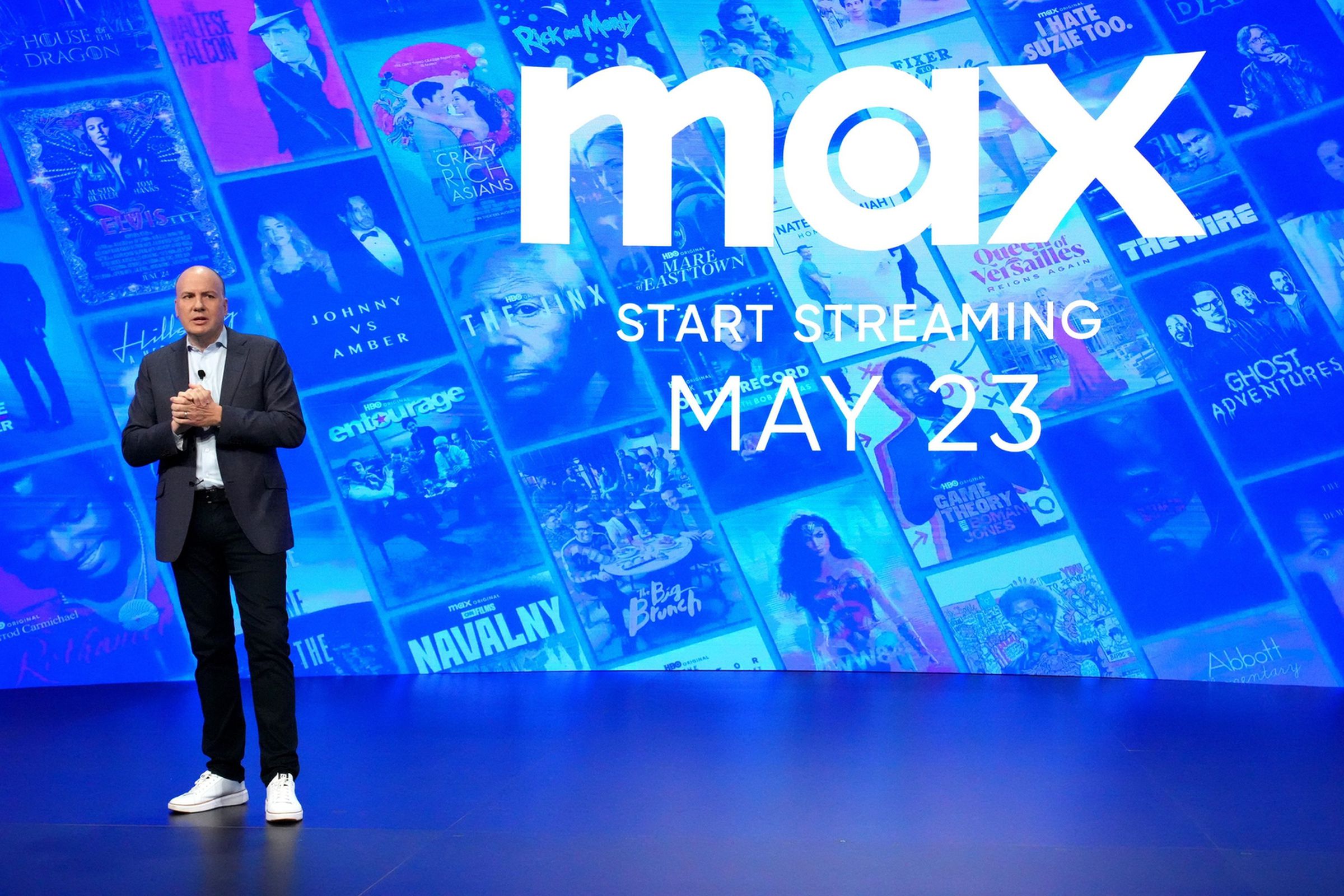 A picture of chair and CEO of HBO and Max content, Casey Bloys, standing in front of the Max logo.