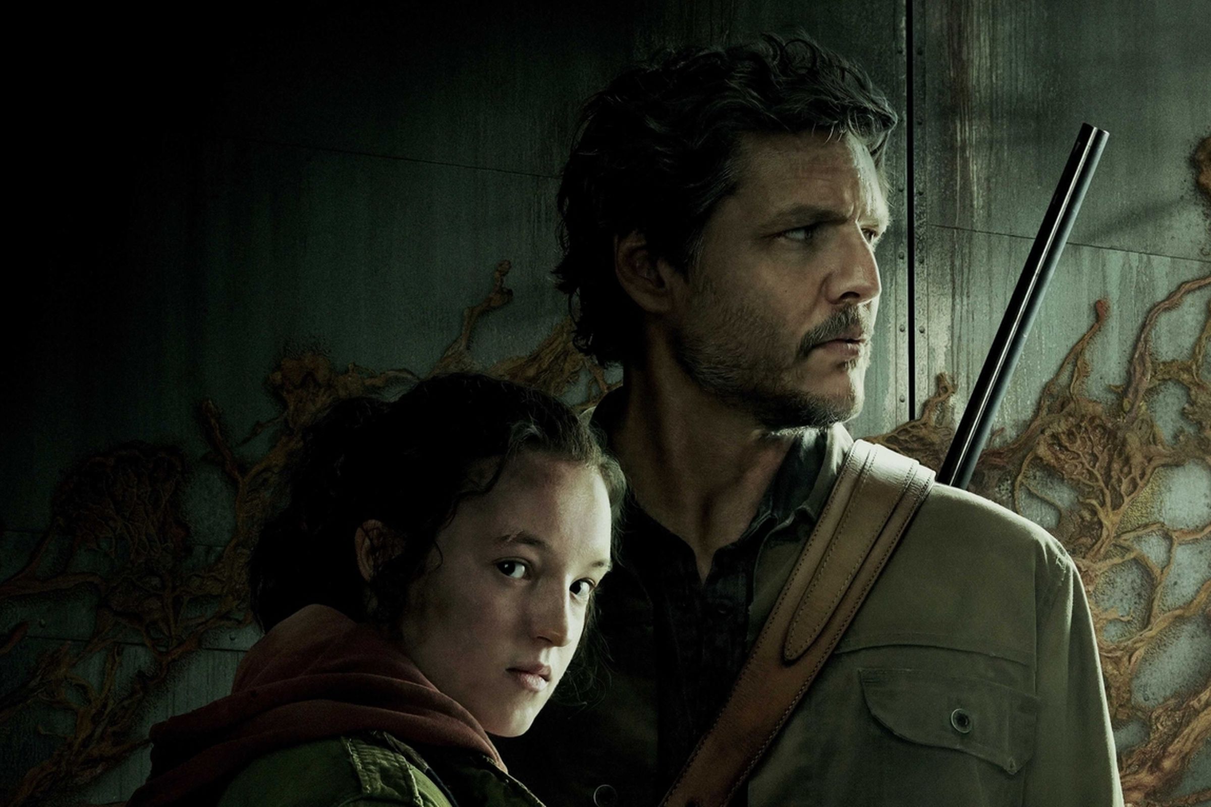 Bella Ramsey (Ellie) with her head lying against Pedro Pascal’s (Joel) chest as he holds up a gun and looks the other way.
